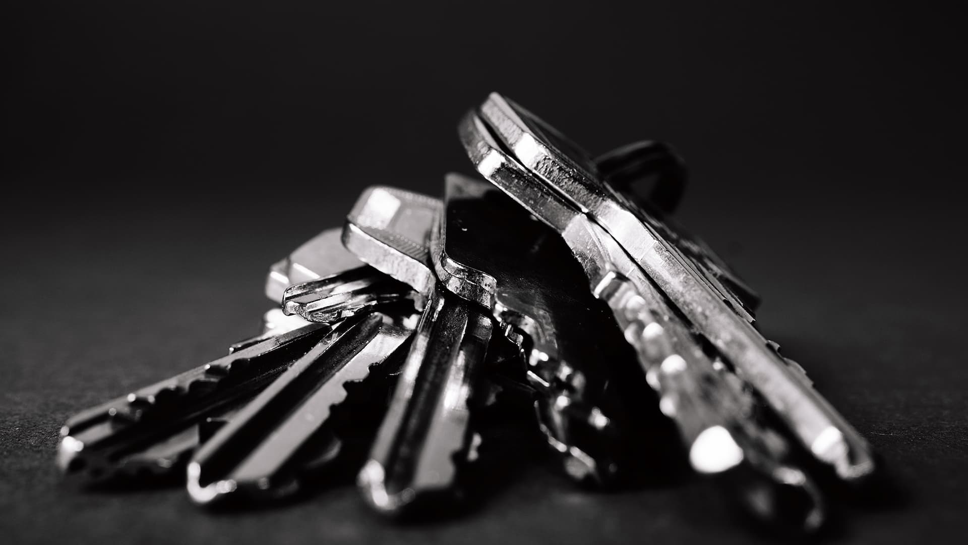 Närbild av nyckelknippa med nycklar i rostfritt stål mot svart bakgrund.